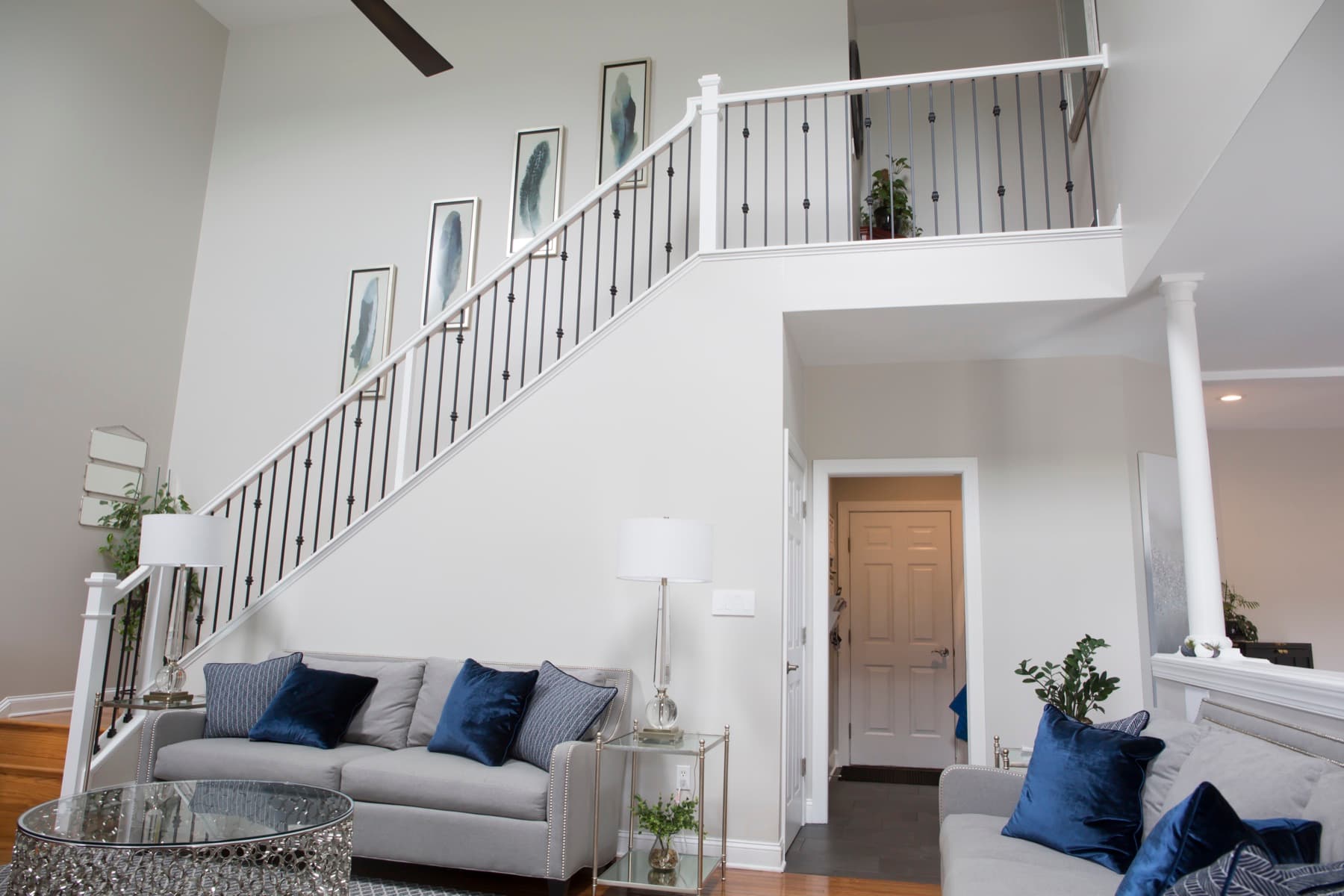 Two-story foyer staircase with knuckle-pattern iron balusters and white handrail over a living room — Center Valley residence