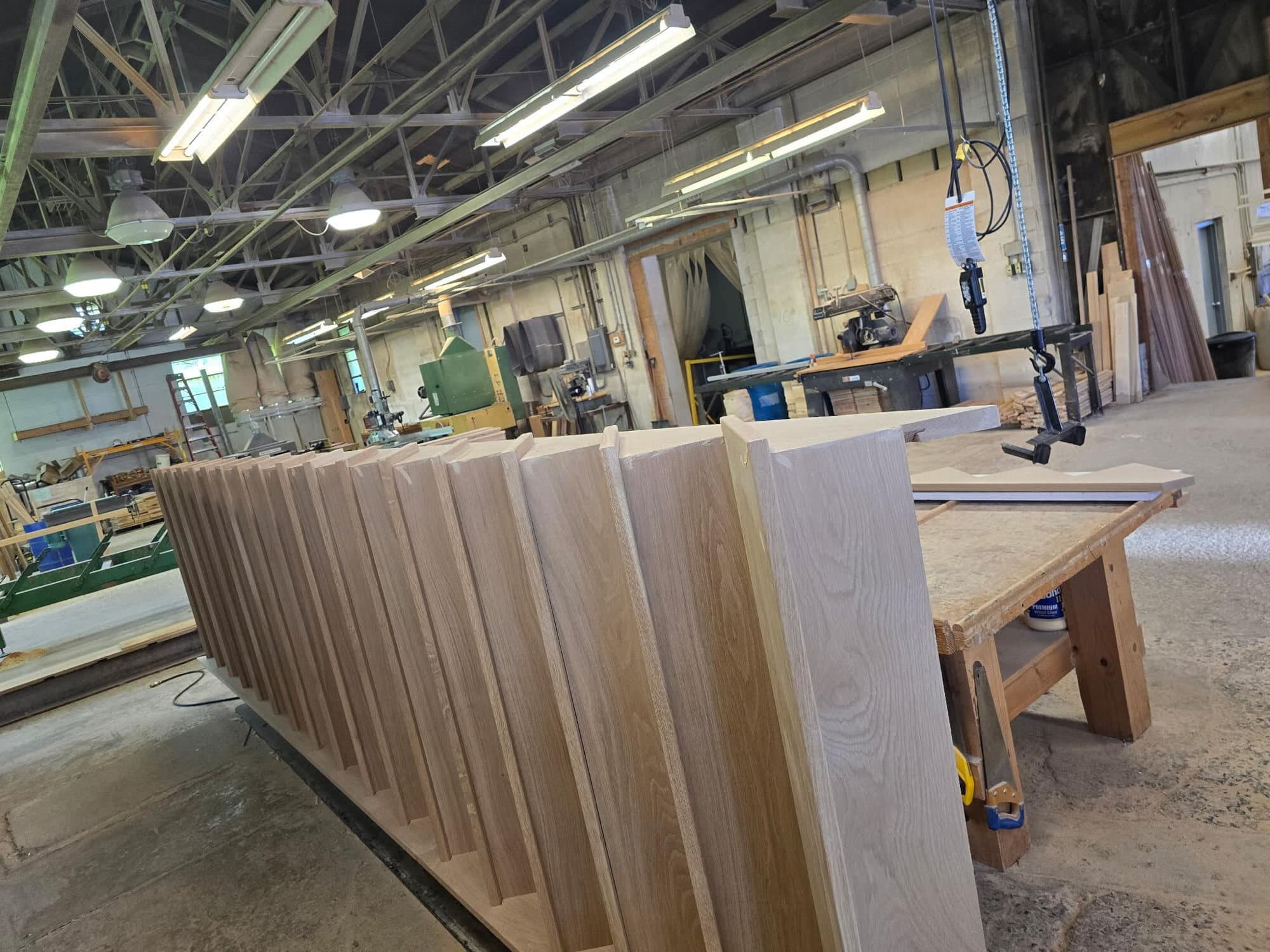 Routed white-oak stair stringers stacked on a bench in the Whitehall shop